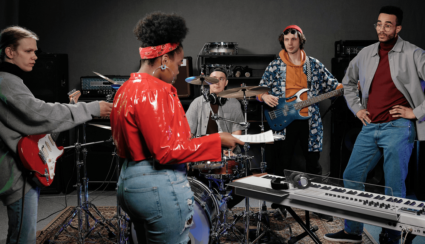 Vibrant diverse band practicing in music studio with instruments, including guitar, keyboard, and drums, highlighting collaboration and creativity in music production.
