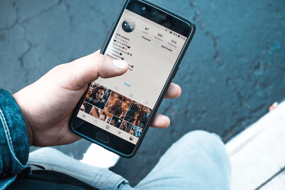 Stylish person browsing Instagram on smartphone, social media marketing for musicians, digital branding, music artist promotion, Hypebot music industry insights, social media engagement for artists, music marketing strategies.