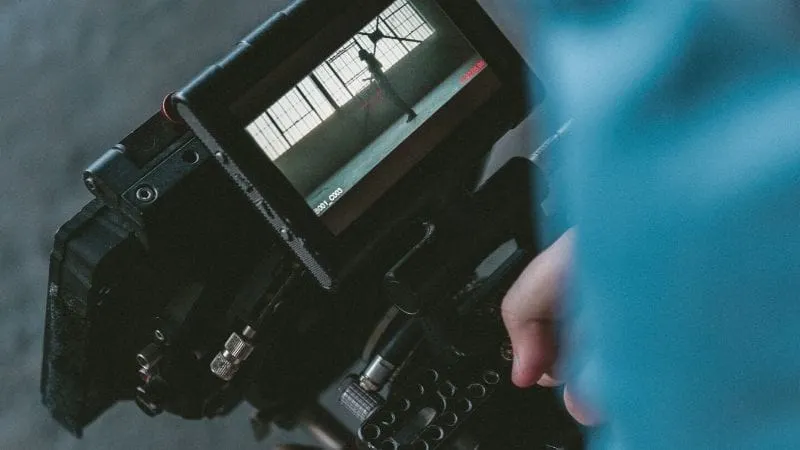 DSLR camera showing live view screen with reflection of a dancer in a studio, capturing music video content.