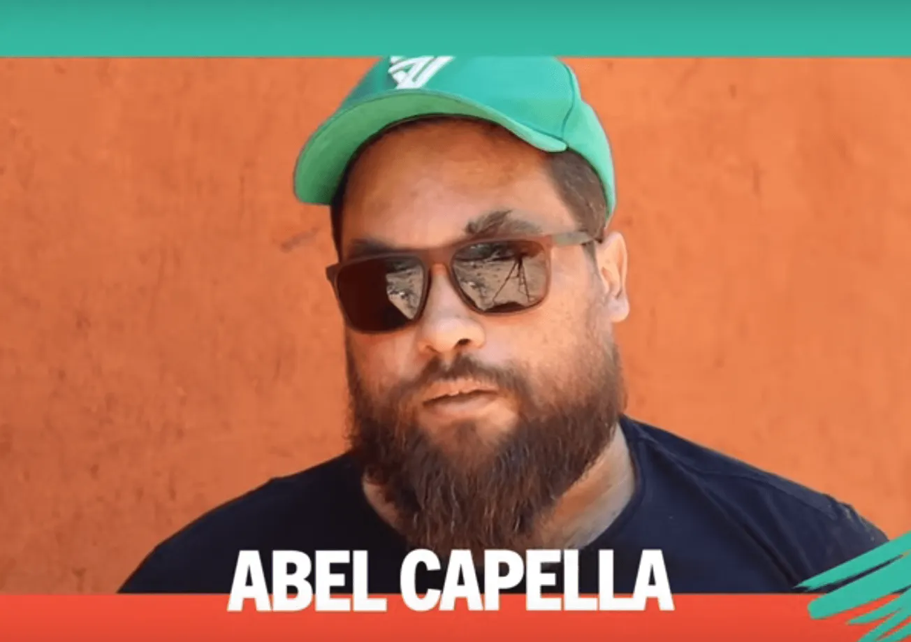 Bearded man wearing sunglasses and green cap, outdoor photo, music industry professional, promotional image for Abel Capella,
